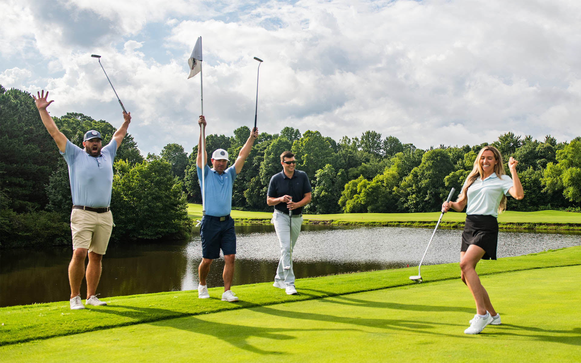 Four adult golfers celebrate a successful birdie putt during Game On Golf Lessons, showcasing the joy and success of our program at Invited country club locations nationwide.